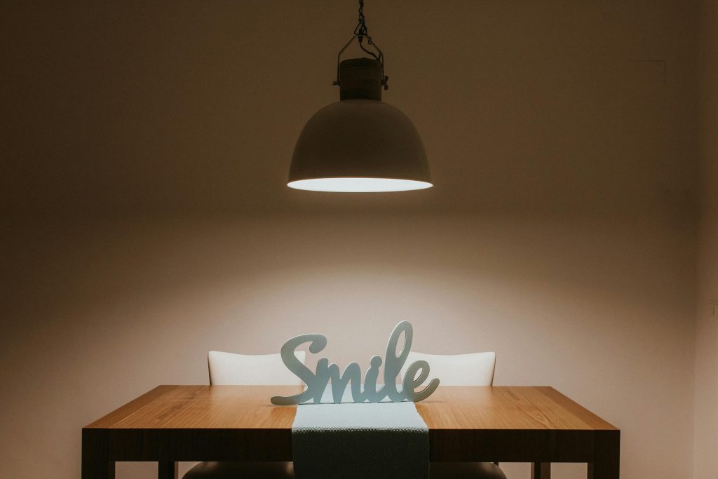 Stylish interior featuring a wooden table, modern lamp, and 'Smile' decor for a warm ambiance.